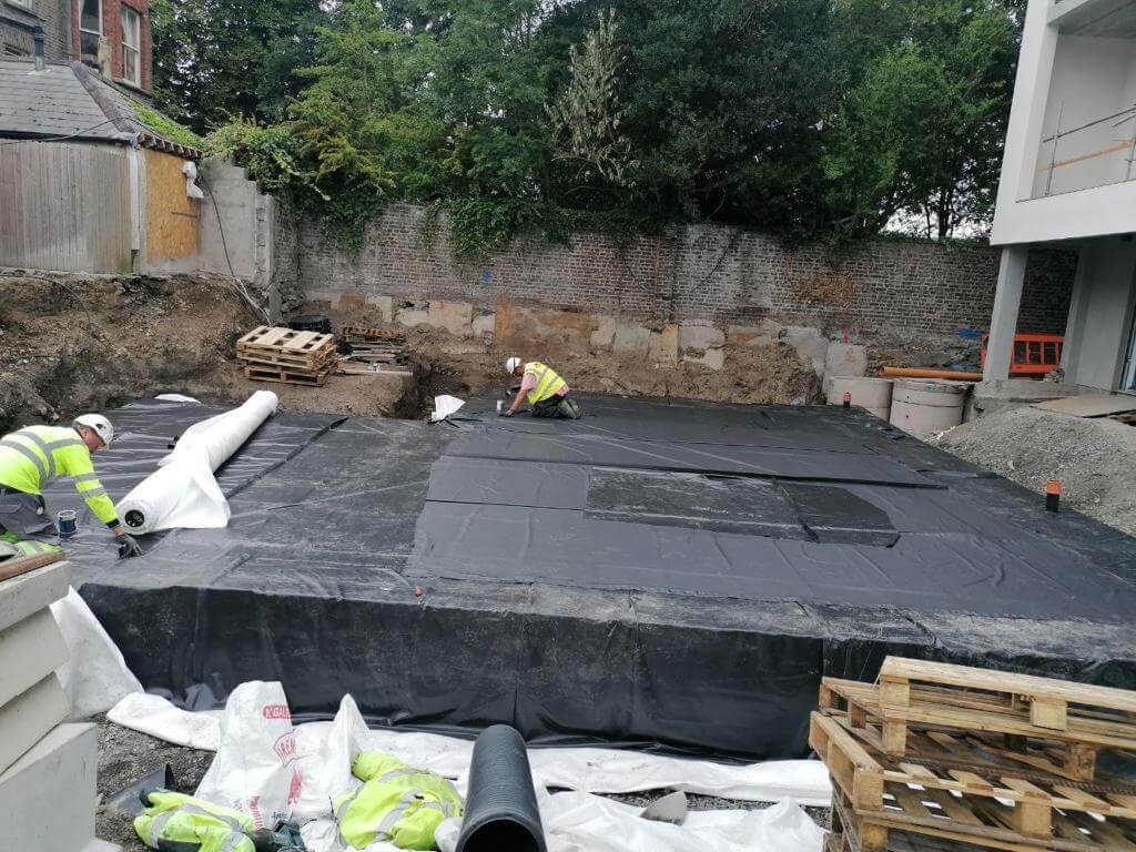 Construction site with workers, wooden pallets, and white material in a pit